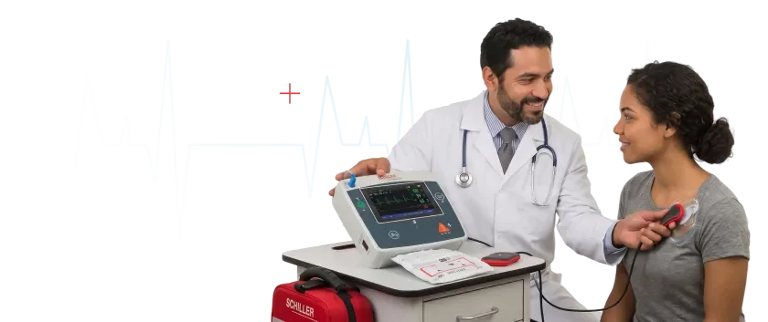 Médico revisando un monitor desfibrilador Schiller junto a una paciente